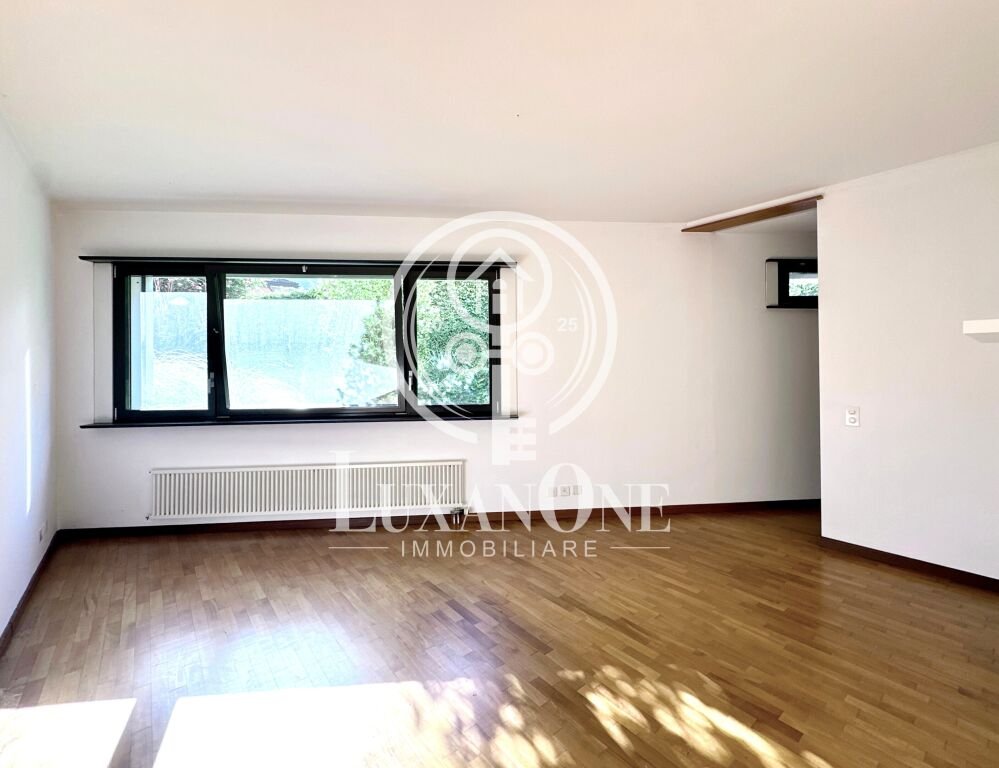 Heller leerer Wohnraum mit großem Fenster und Parkettboden